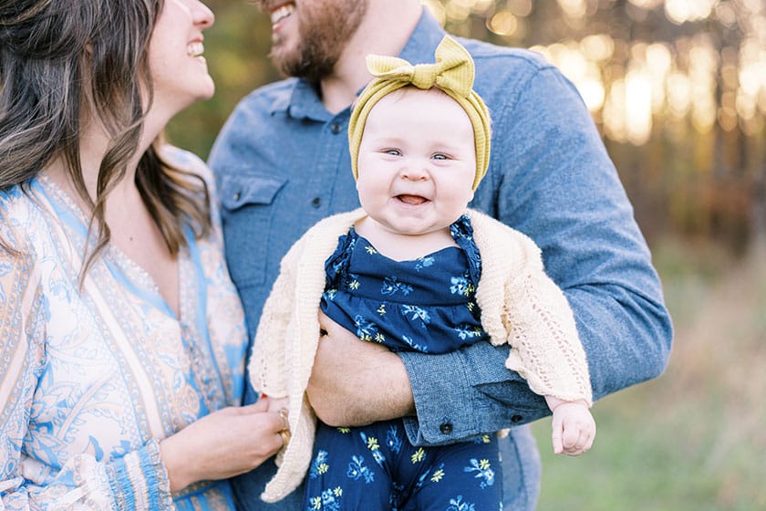 couple smiling at each other and holding happy baby