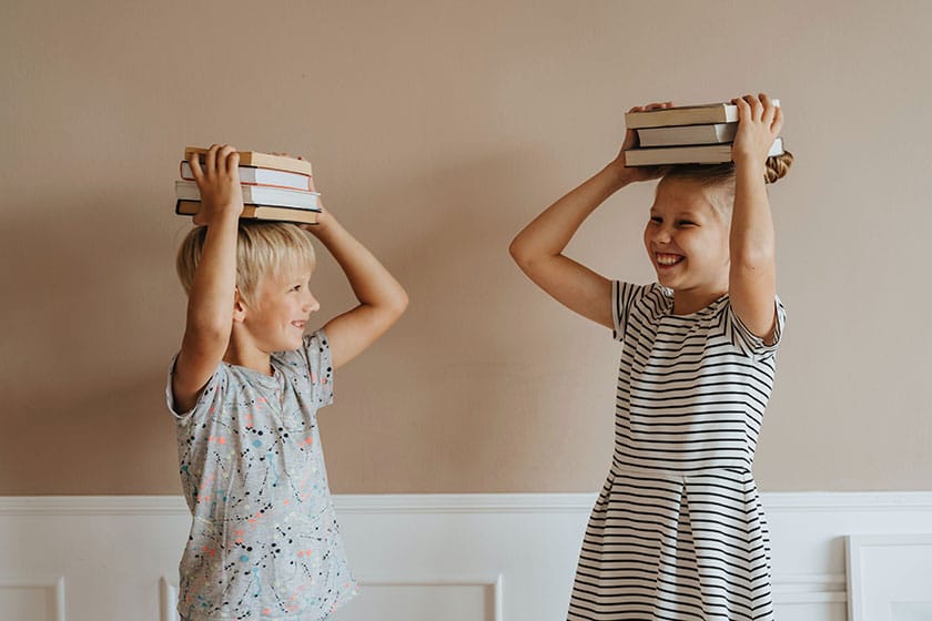 laughing children holding books on their heads