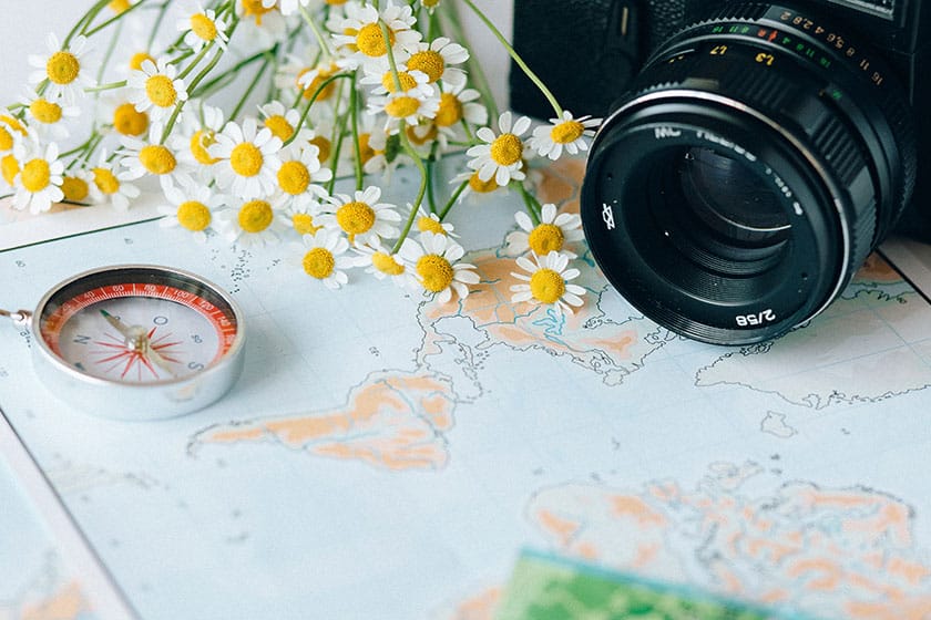 camera, flowers, and compass sitting atop a world map