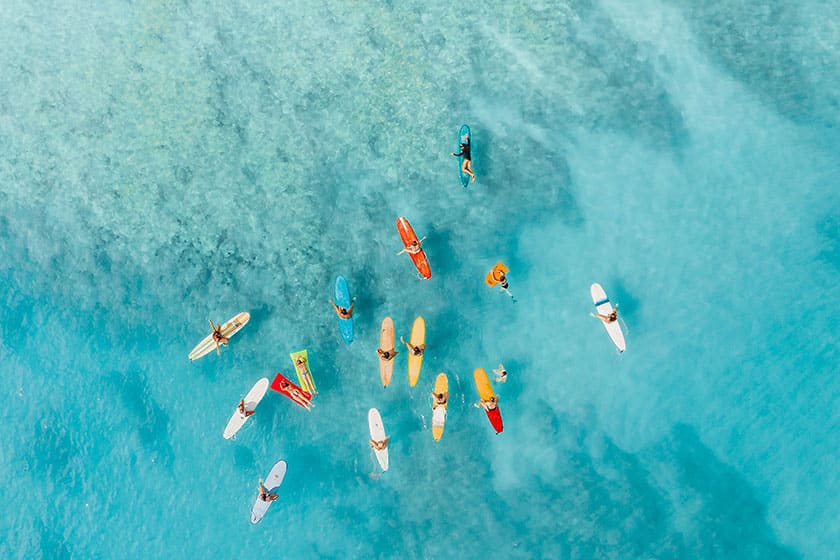 overhead photo of people on surfboards and floats in tropical water
