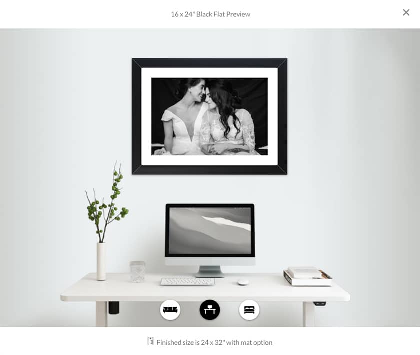 black and white framed print of two brides hanging on the wall above a computer desk 