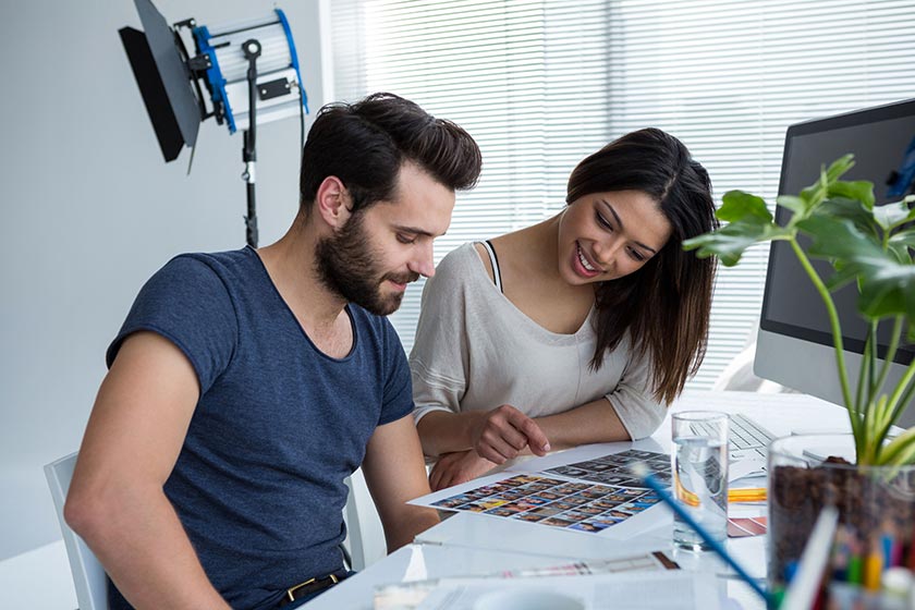 two photographers reviewing session proofs in a home studio