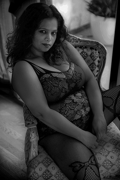 black and white boudoir image of woman in lace lingerie seated in a chair