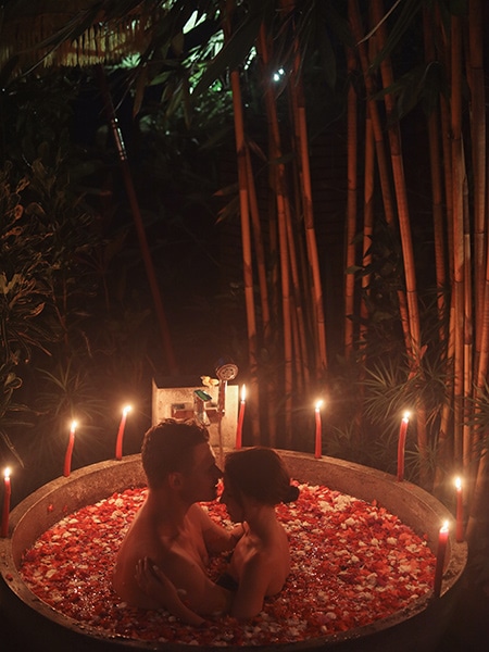 valentines day themed couple boudoir photo in rose petal bath with candles