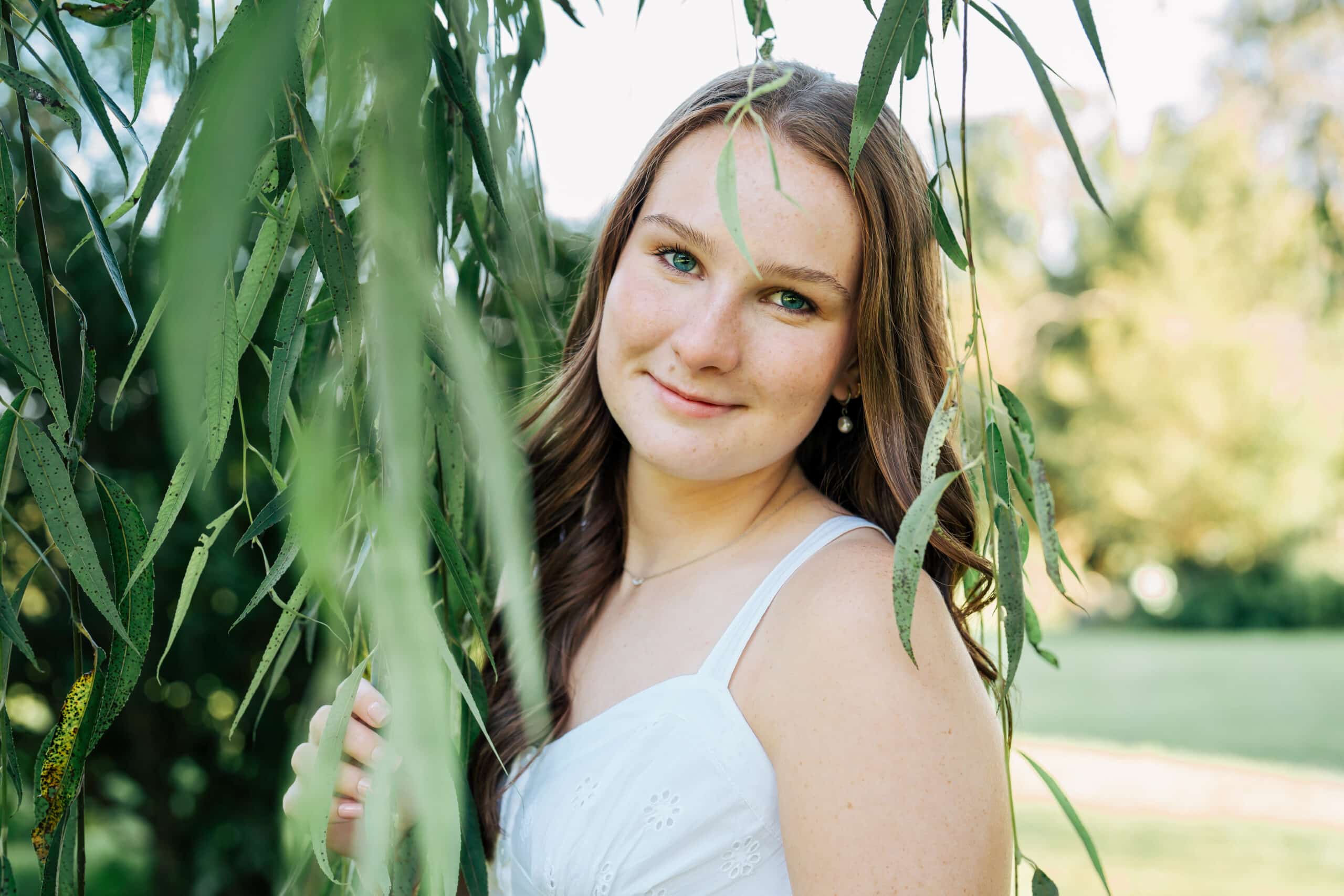 Senior portrait of girl in white dress surrounded by willow branches