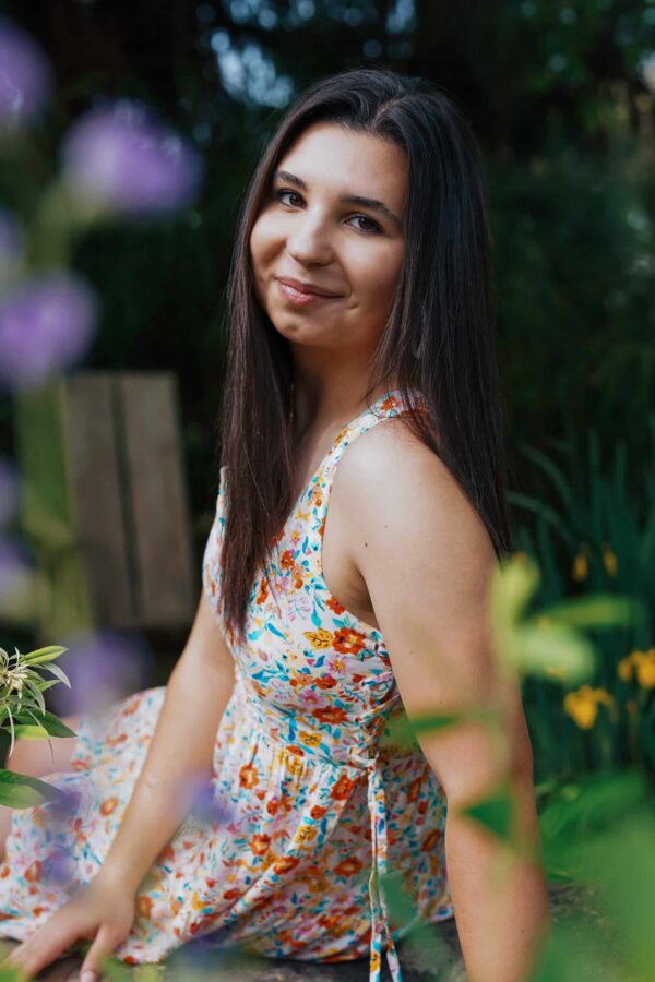 Senior portrait of dark haired girl sitting and leaning on one arm
