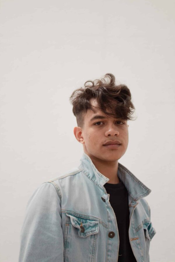 teenage boy wearing denim jacket in front of white background
