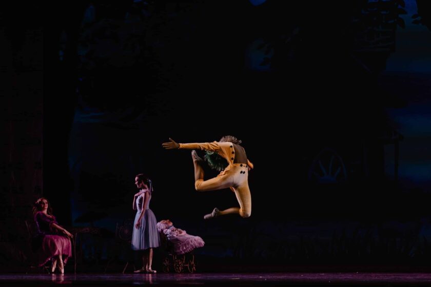 modern dancers in costumes, one of whom is leaping across the stage