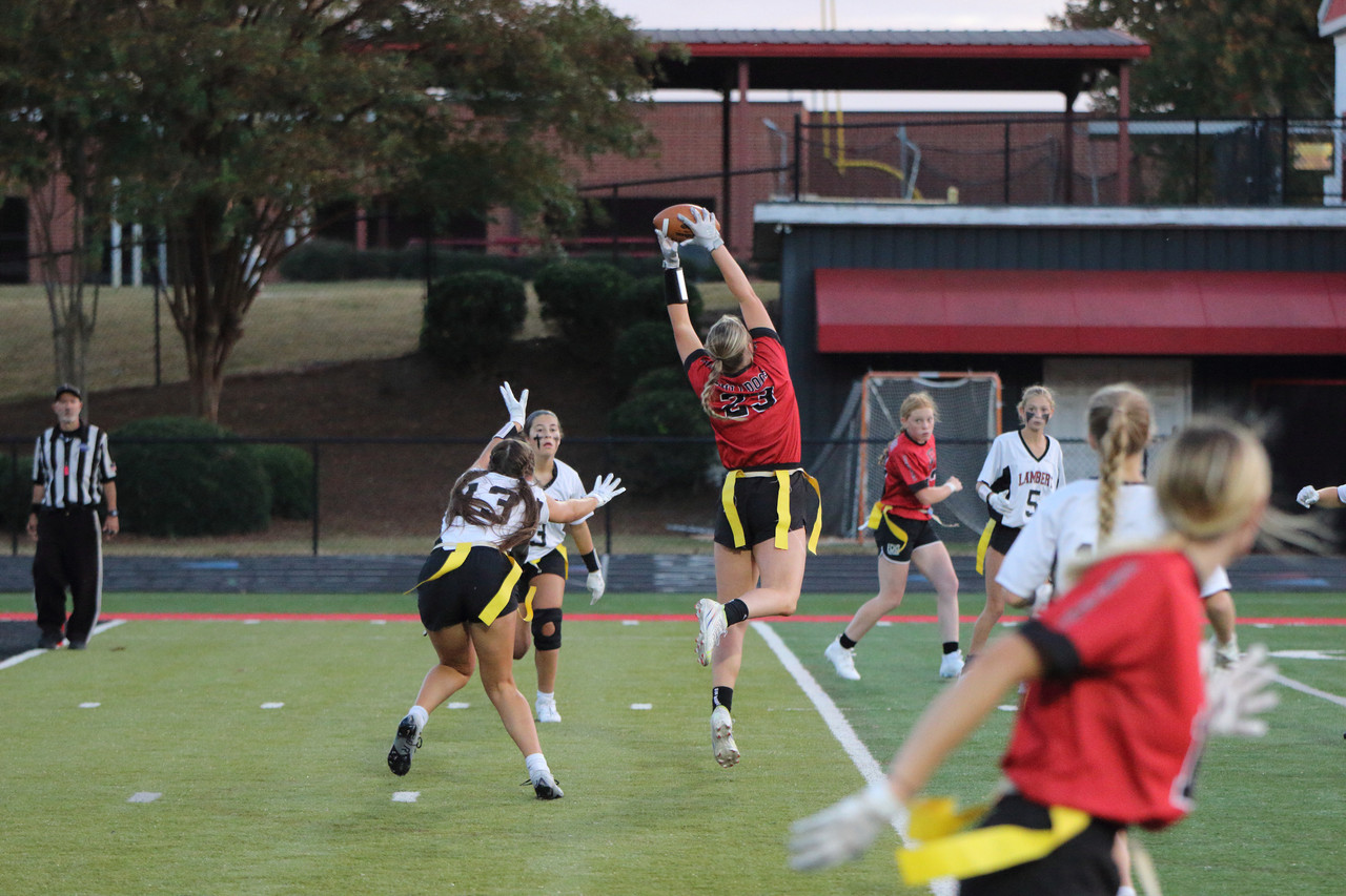 girl jumping to catch football during a touch football game; photographed by Jonathan Leitner