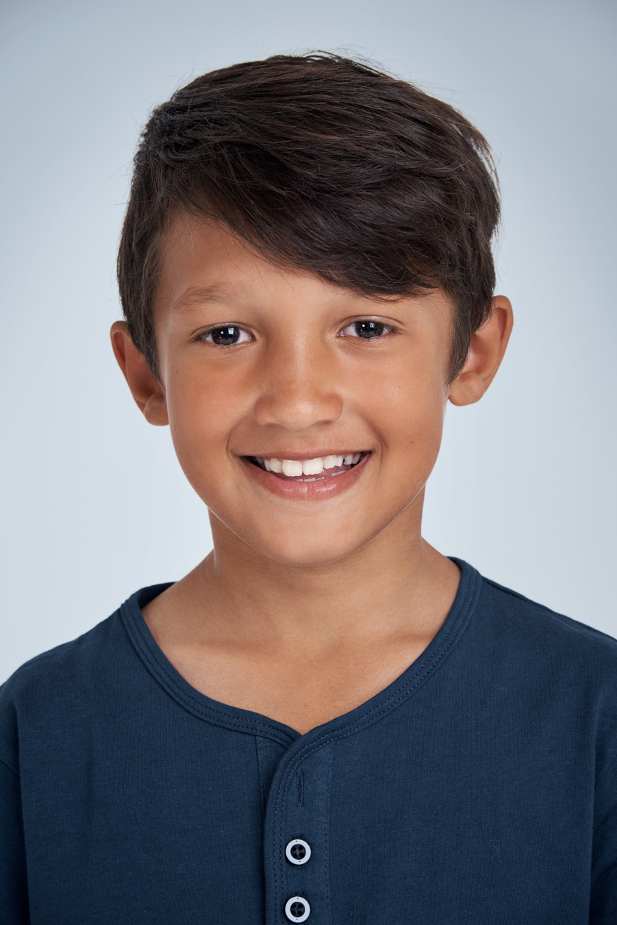 school portrait of smiling young boy with dark hair wearing blue henley shirt