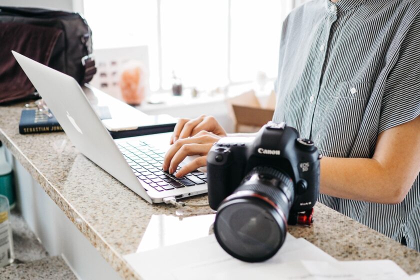 woman using laptop on marble countertop beside Canon camera
