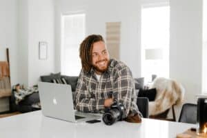 man in black and white plaid dress shirt sitting beside macbook