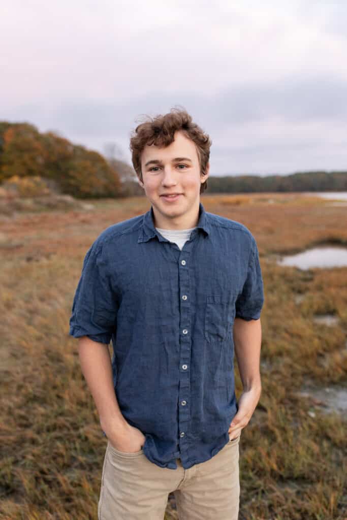 teen boy wearing a blue shirt and standing with his hands in his pockets