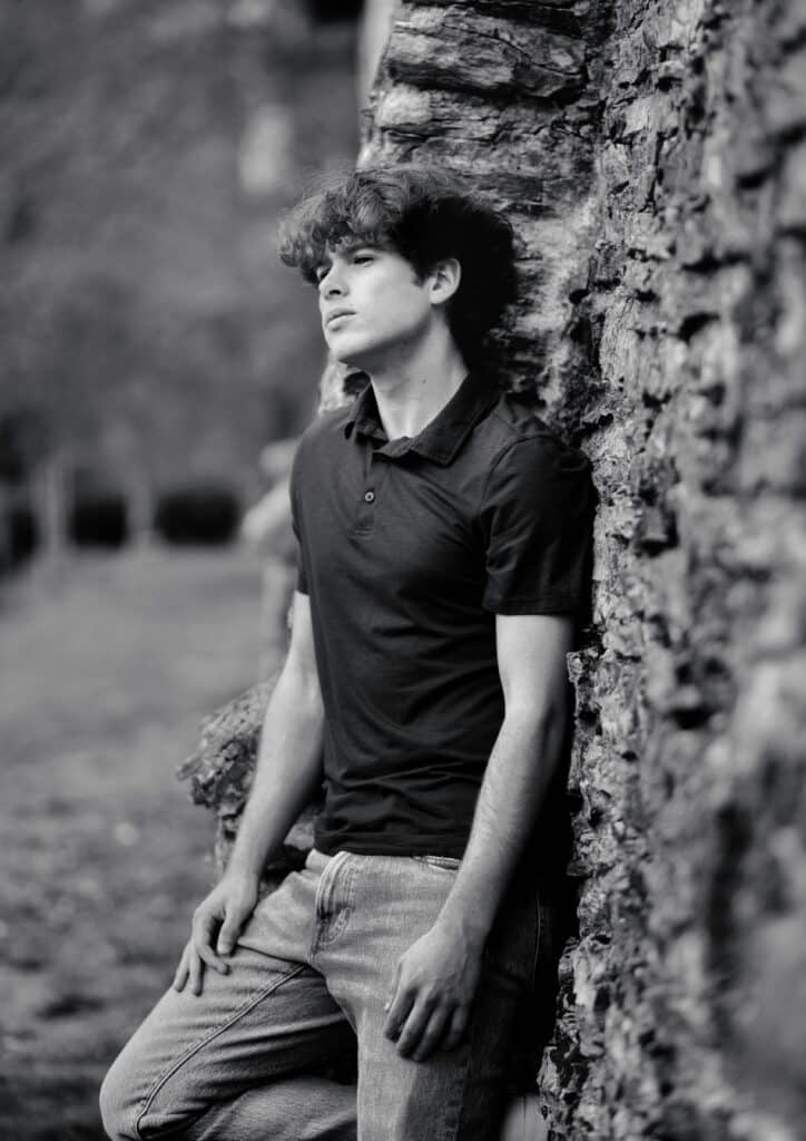 b&w portrait of senior boy leaning against tree