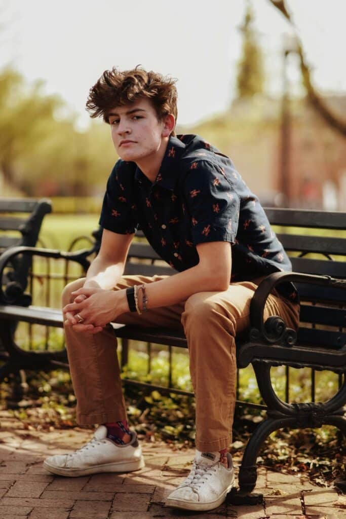 senior boy sitting on bench elbows on knees
