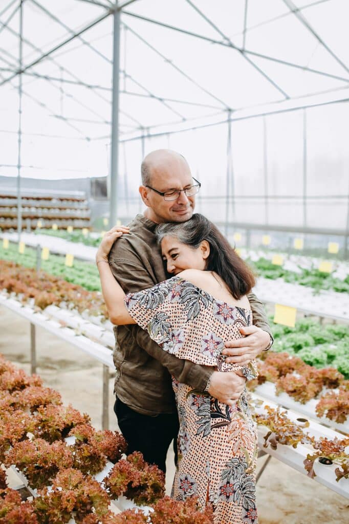 middle age man and woman hugging inside greenhouse