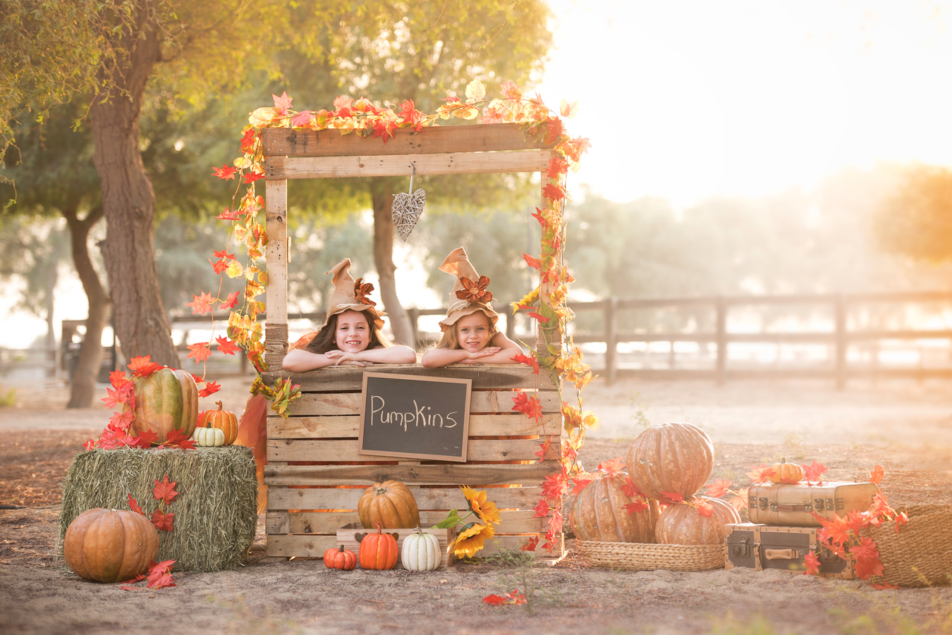 Two girls in witch hats at a rustic pumpkin stand