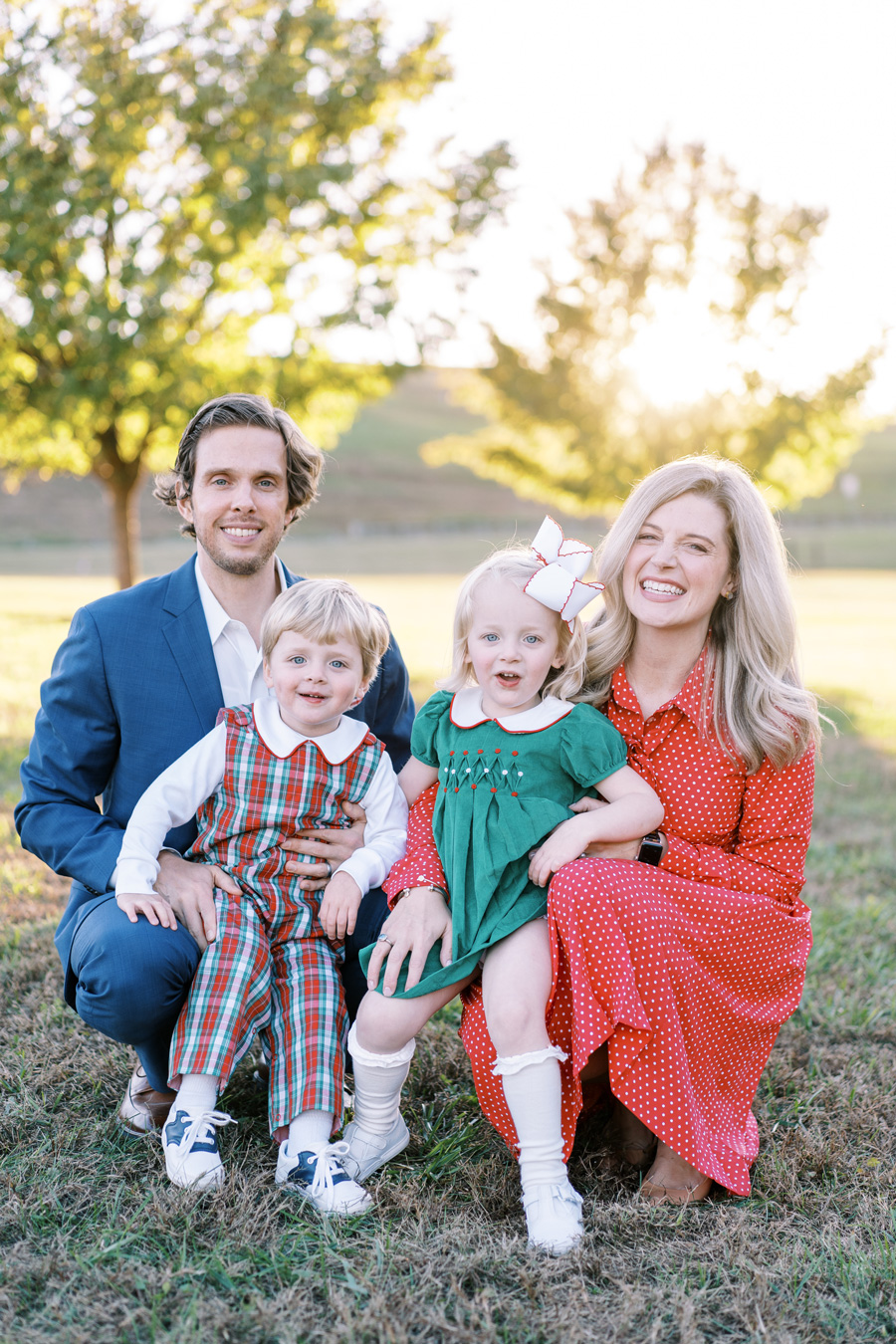 Family portrait: parents and two young children in festive clothing, outdoors on grass