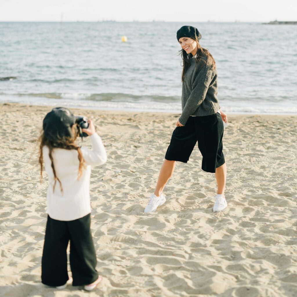 Daughter Taking Pictures of Posing Mother on Beach