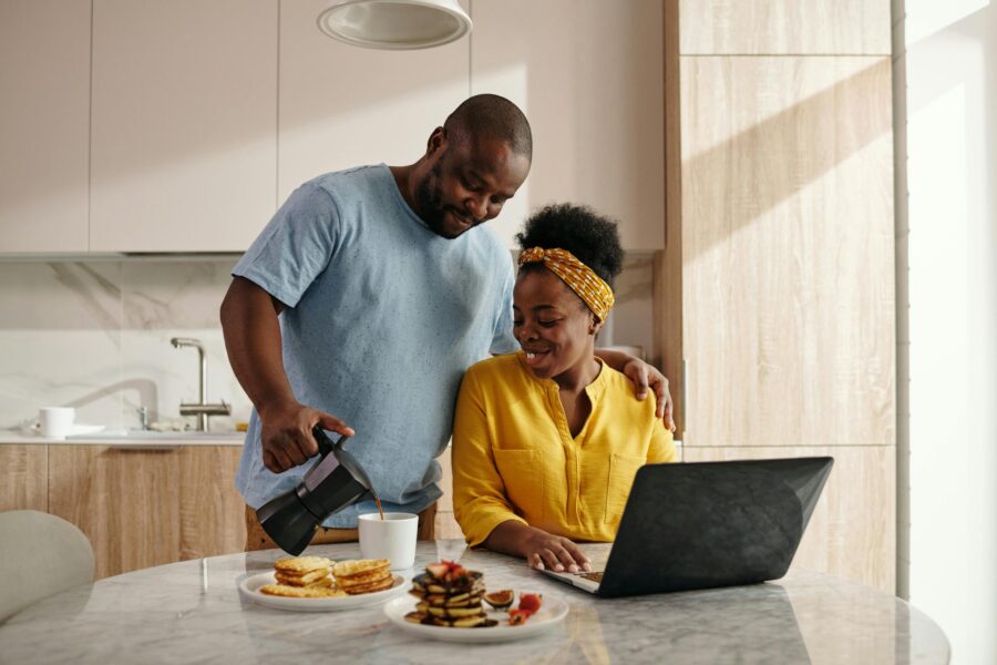 Man Serving Coffee to a Woman on laptop at breakfast