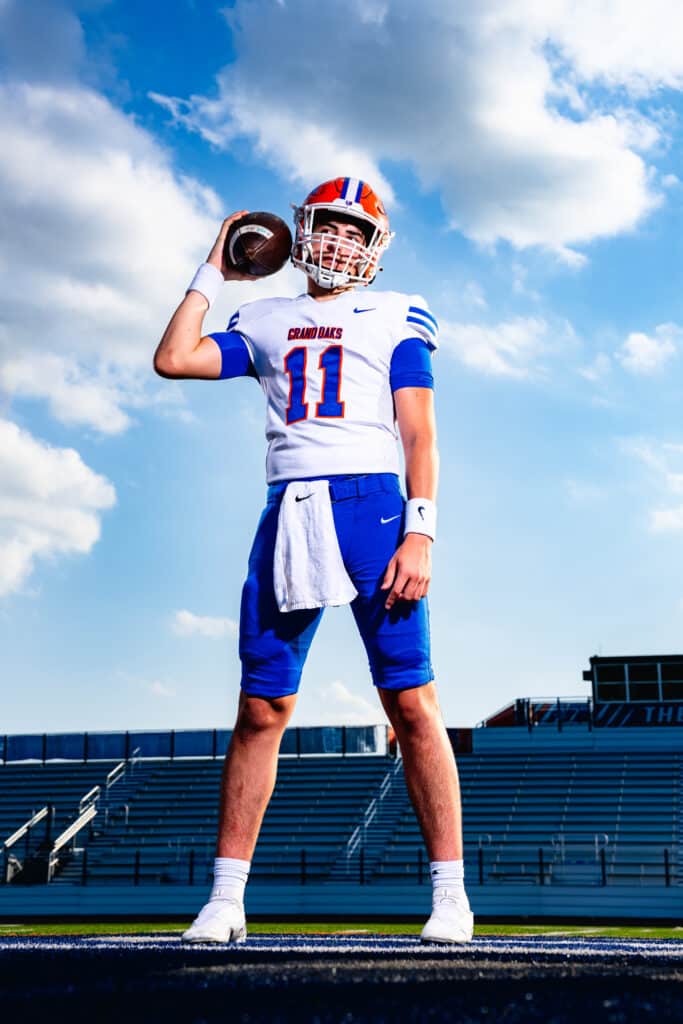Football player in blue and white uniform holding ball. Photography by Seth Fontenot