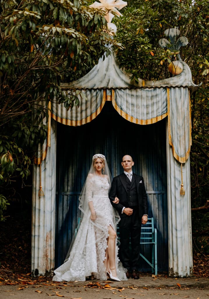 wedding couple with serious faces posed in stylized tent. Photo by Steve Bridgwood