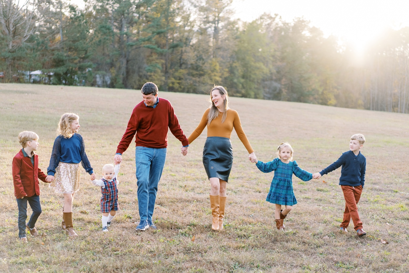 Family of seven wearing fall colors and walking in a field hand in hand Edwards 2024 Elizabeth Tate Photography
