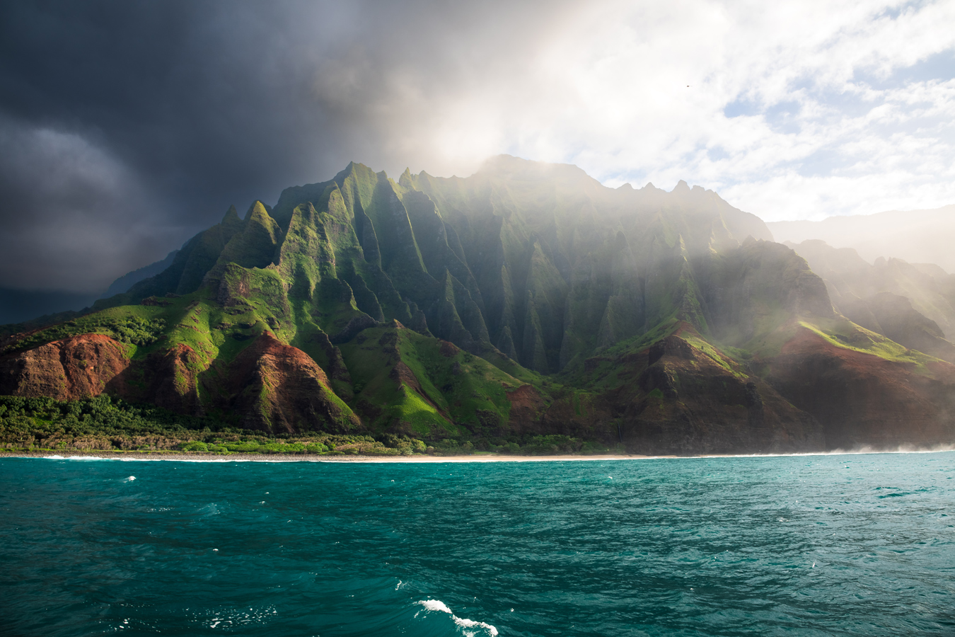 Ocean view of Na Pali Coast, Kauai: dramatic cliffs, lush green vegetation, and dark clouds