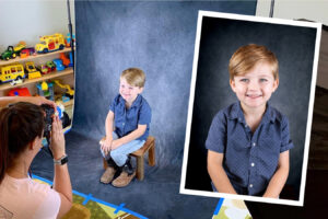 Young boy's photo shoot: A photographer captures a smiling toddler seated on a stool against a dark backdrop. photo by Caroline Stubbs