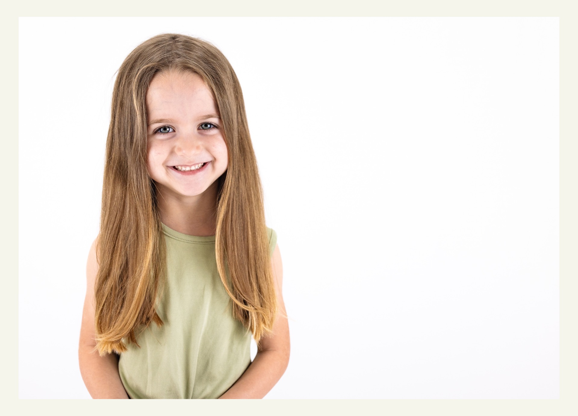 school portrait of a preschool girl with light brown hair wearing a green shirt in front of a white background. Photograph by Caroline Stubbs.