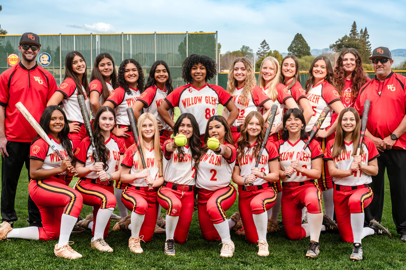 A group photo of the Willow Glen softball team and coaches. The team wears red and white uniforms and holds bats or softballs. The coaches wear red shirts with WG on them.