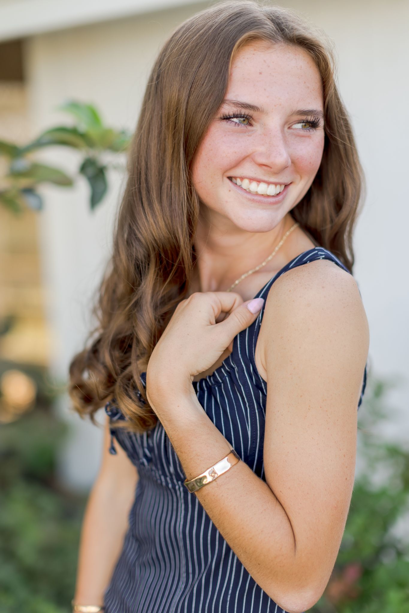 Smiling woman with long brown hair wearing a striped dress outdoors