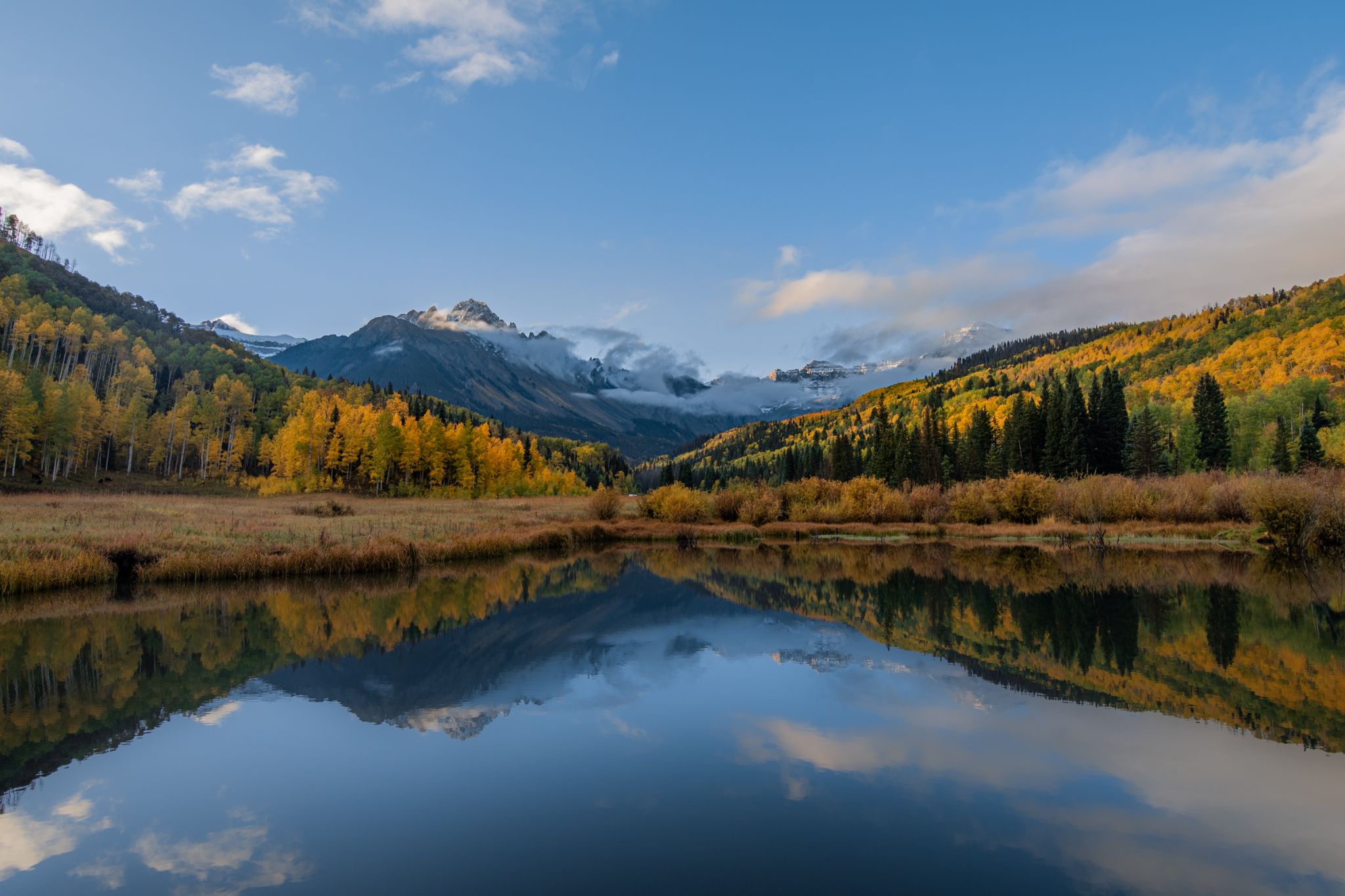Autumn Colorado mountain landscape reflected in a tranquil lake beneath a blue sky